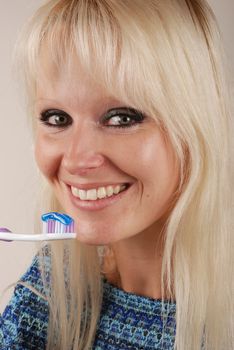 Young blonde woman brushing her teeth