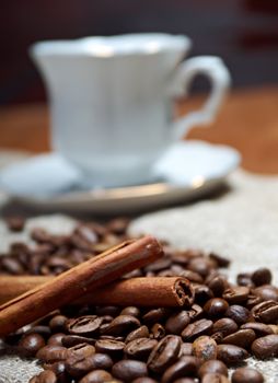 Coffee cup with cinnamon and coffee beans background