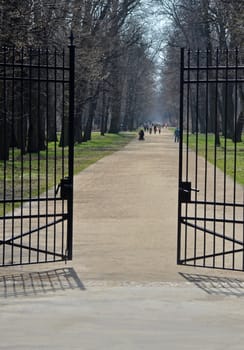 Entrance to Łazienki Royal Park in Warsaw. Far away walking people.