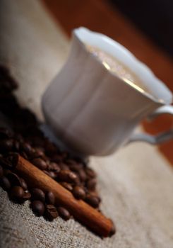 Coffee cup with cinnamon and coffee beans background