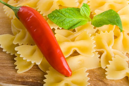 Golden raw dried Italian pasta with other ingredients on kitchen desk.