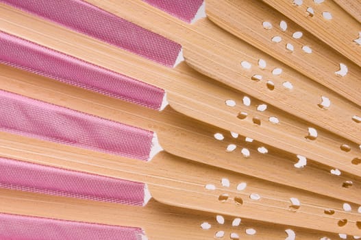 Close-up of a pink wooden hand made fan on white.