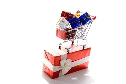 shopping cart with gift box wrapped in colored paper and ribbon on white background