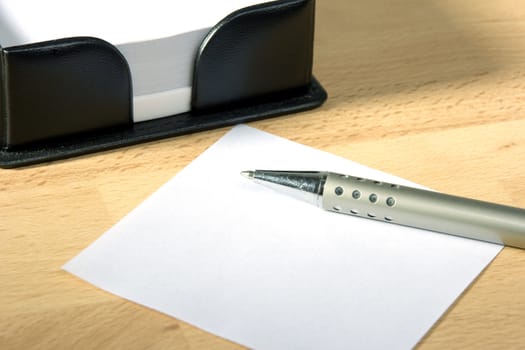 White sheet of paper and a silver pen at work desk