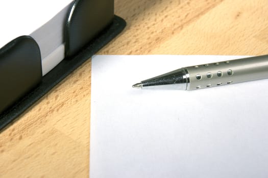 White sheet of paper and a silver pen at work desk