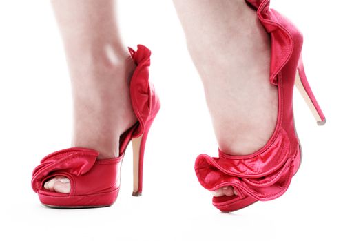 Close up shot of womans feet in red stilettos on an isolated white background.