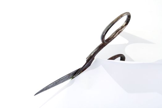 Old rusty steel scissors cut paper on white background