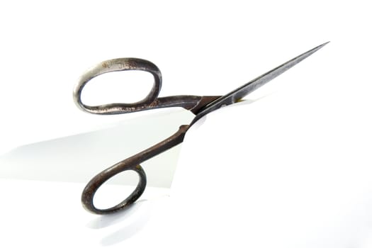 Old rusty steel scissors cut paper on white background