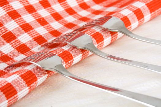 Shiny stainless steel forks on checkered fabric