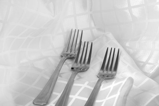 Shiny stainless steel forks on white fabric