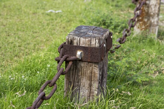 Decorative fence made of cracked wooden beams and rusty iron chain