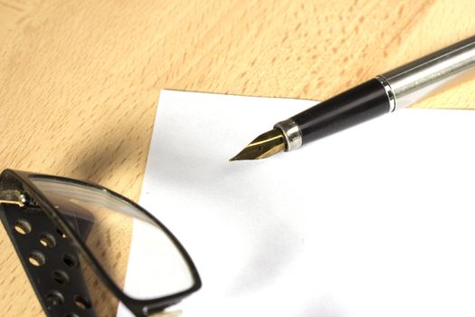 A sheet of white paper and fountain pen with gold nib at the work desk