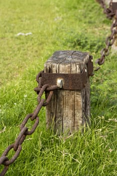 Decorative fence made of cracked wooden beams and rusty iron chain