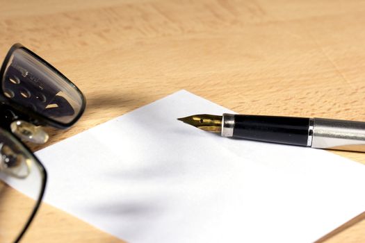 A sheet of white paper and fountain pen with gold nib at the work desk