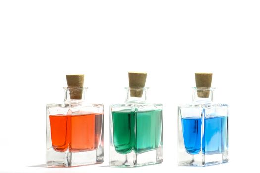 Clear glass vials filled with red, green and blue liquid on a white background