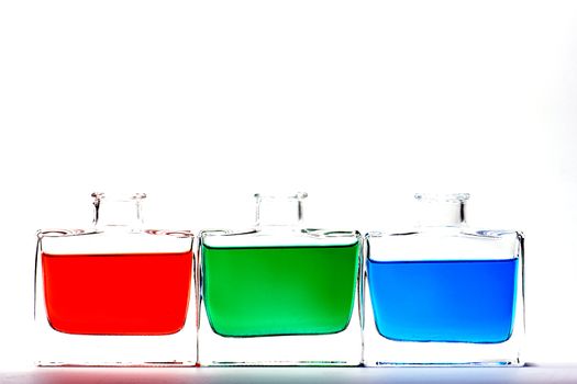 Clear glass vials filled with red, green and blue liquid on a white background