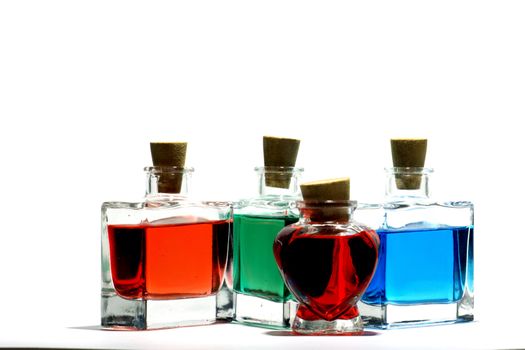 Clear glass vials filled with red, green and blue liquid on a white background