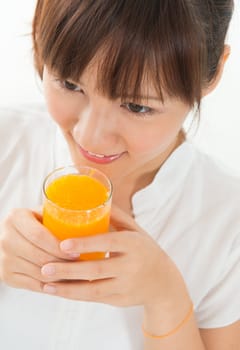 Young Asian female drinking orange juice, isolated on white.