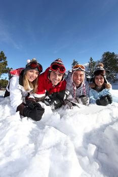 Four friends laying in the snow