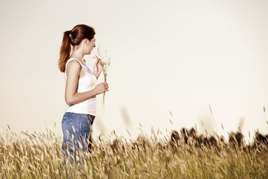 Outdoor portrait of a beautiful woman holding flowers on a summer day