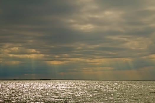 Rays of the sun pierce the clouds and sparkle on the waters of the Oregon Inlet into Pamlico Sound on the outer banks of North Carolina