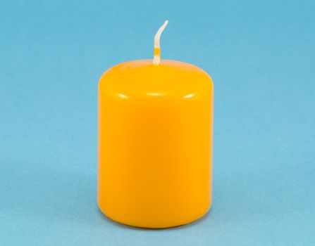 yellow thick simple wax candle with wick on blue background