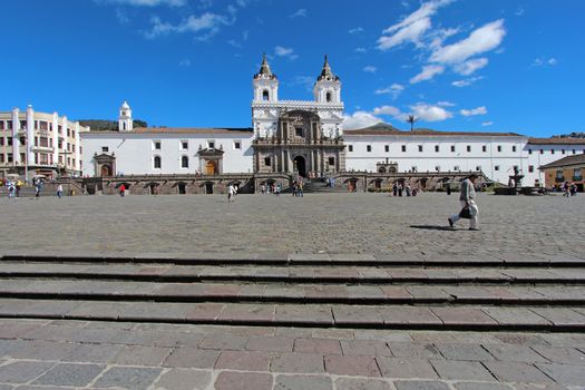 QUITO, ECUADOR - JUNE 1: People go about their business in the plaza in front of the church and convent of San Francisco in the historic part of downtown Quito, Ecuador against a bright blue sky and white clouds on June 1, 2012