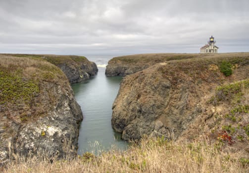 The Point Cabrillo lighthouse near Mendocino, California, with a bay leading into the Pacific Ocean against a dramatic sky