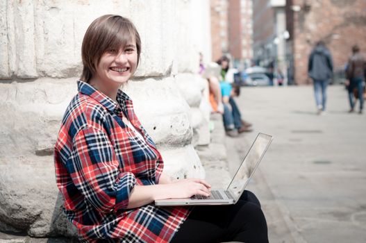 young woman using notebook in the street