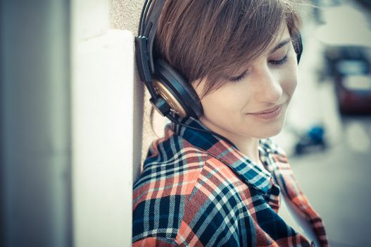young hipster woman listening to music on balcony