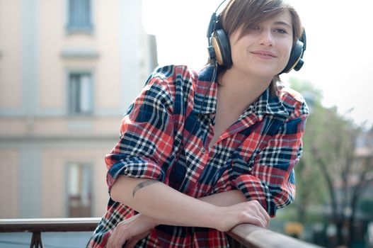 young hipster woman listening to music on balcony