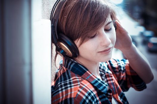 young hipster woman listening to music on balcony