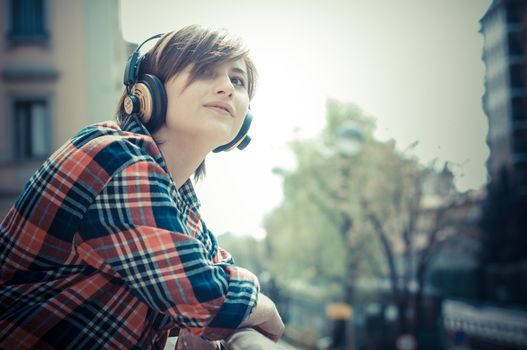 young hipster woman listening to music on balcony