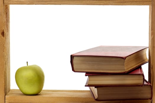 Some books with dark red hardcover and green apple in a wooden frame on white background