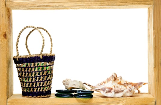 Wicker, green pieces of glass and sea shells inside rough wooden frame on white background