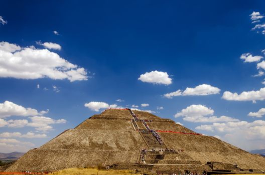 View of tourist climbing the pyramid of the sun set against a deep blue sky