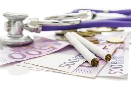 Cigarettes and stethoscope on Euro money. With copy space. Concept of health and financial damage smoking makes.