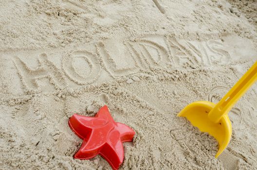 Word holidays written in sand. Concept of happy summer holiday.