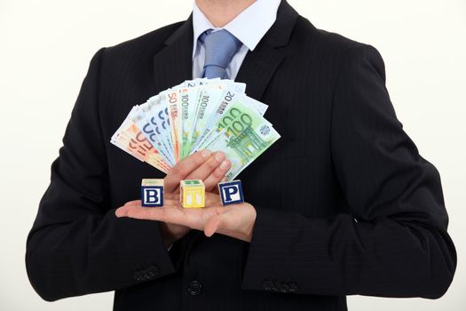 Businessman holding bills and toy blocks