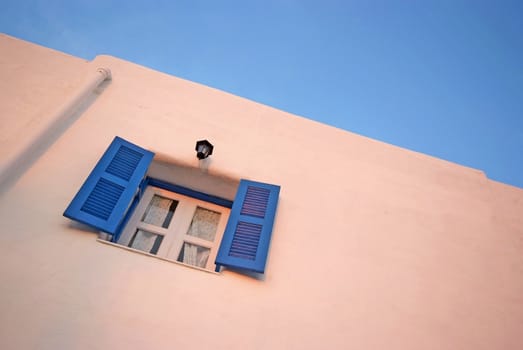 Vintage blue windows on the white wall and blue sky.