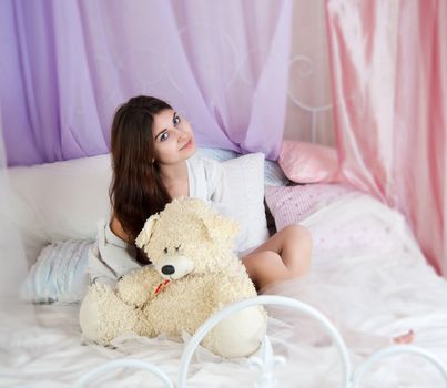 beautiful woman in bed with a white teddy bear
