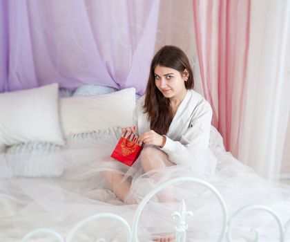 Beautiful woman in bed opening a gift
