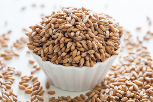 Small bowl filled with spelt grains that spilled over