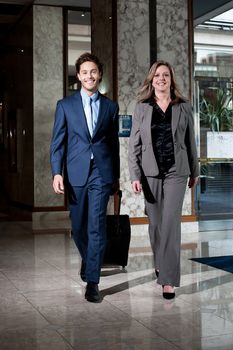 Confident business colleagues entering hotel lobby with lugguage