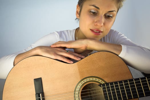 Blond short hair woman woman with white Tshirt playing acoustic guitar