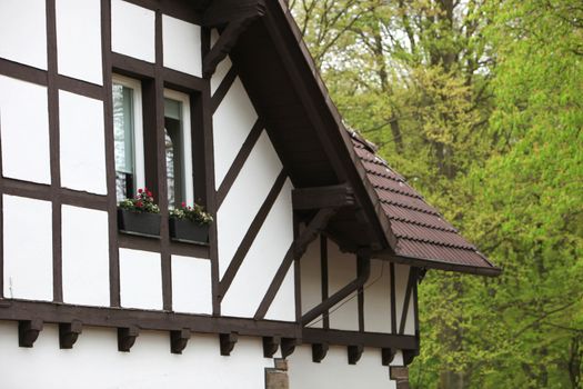 Detail of a timber frame house showing the exterior wall with a pretty window and window box with flowers