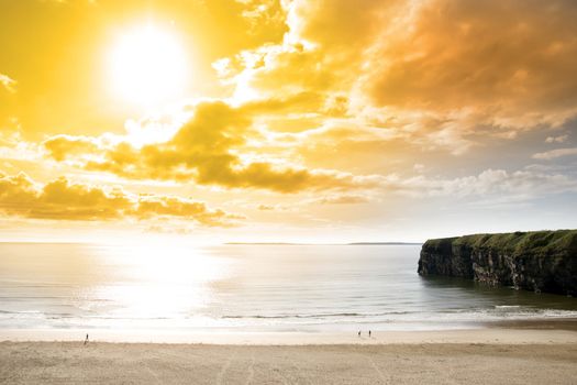 tourists walking the Ballybunion beach near cliffs in county Kerry Ireland on a beautiful summers day