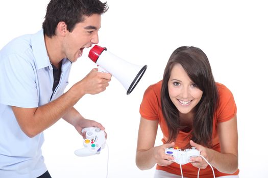 Man shouting into megaphone as girlfriend plays video game