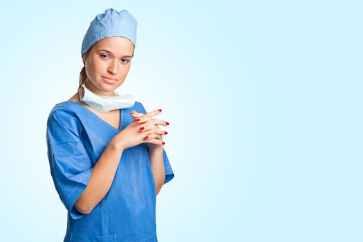 Young female surgeon with scrubs, holding a face mask on a white background