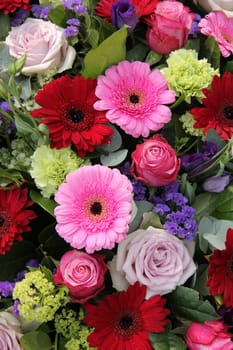 Red and pink gerberas, together with purple roses and other flowers in a wedding arrangement